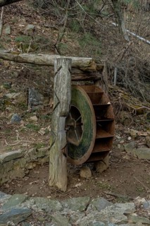 Old, rusted, metal waterwheel in mountainside public park