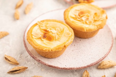 Traditional portuguese cakes pasteis de nata, custard small pies with almonds with cup of coffee on
