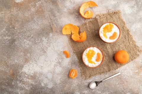 Grained cottage cheese with tangerine jam on brown concrete background and linen textile. top view,