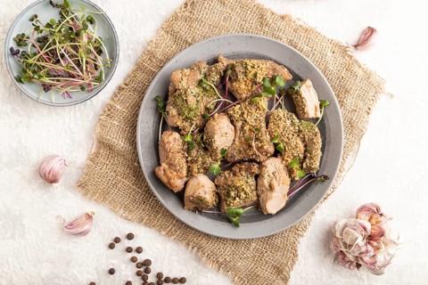 Stewed turkey fillet with garlic and sprouts of radish on white wooden background and linen textile