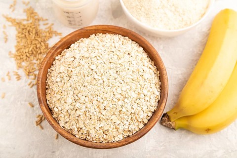 Powdered milk and oatmeal, banana baby food mix, infant formula, pacifier, bottle, spoon on gray