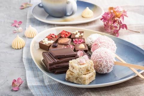 A pieces of homemade chocolate with coconut candies on a blue and brown textile. side view, close