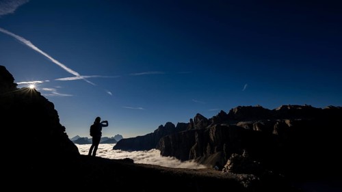 Mobile phone photographer on ridge with Dolomites mountains in the background, Corvara, Dolomites,