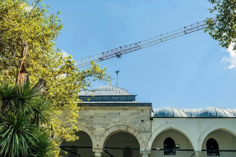 Crane arm over domes of mosque against blue sky in Istanbul, Turkiye