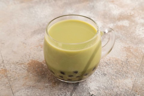 Bubble tea with pistachio and caramel in glass on brown concrete background. Healthy drink concept.