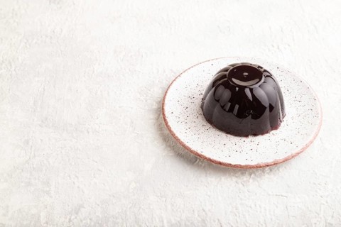 Black currant and grapes jelly on gray concrete background. side view, copy space