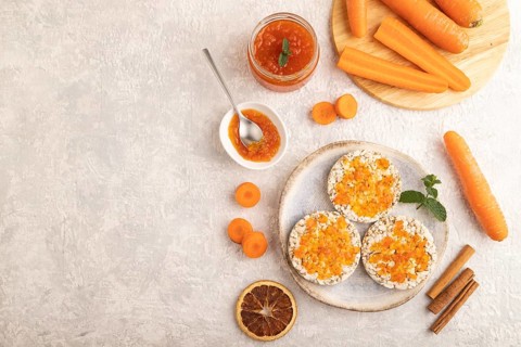 Carrot jam with puffed rice cakes on gray concrete background. Top view, flat lay, copy space
