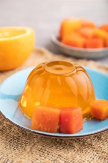 Papaya and orange jelly on gray concrete background and linen textile. side view, close up,