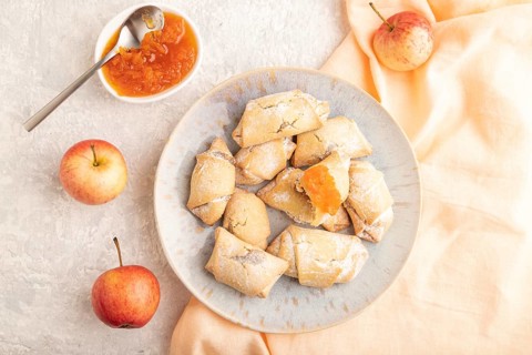 Homemade sweet cookie with apple jam and cup of coffee on gray concrete background and orange linen