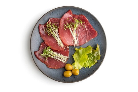 Slices of smoked salted meat with cilantro microgreen isolated on white background. Top view, flat