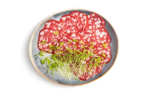 Slices of smoked cervelat salami sausage with spinach microgreen isolated on white background. Top