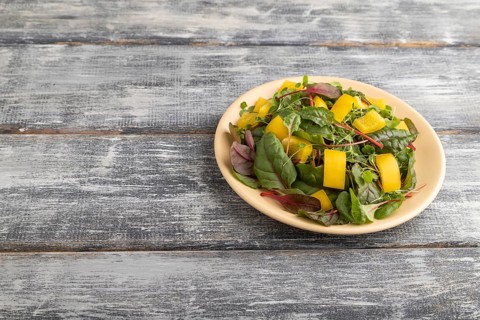 Vegetarian vegetables salad of yellow pepper, beet microgreen sprouts on gray wooden background.