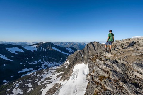 Mountain panorama, glacier remains of Skalabreen, mountaineer at the summit of Skala, Loen, Norway,