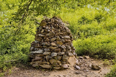 Column of stones and pebble stacks beside hiking trail in recreational forest in South Korea