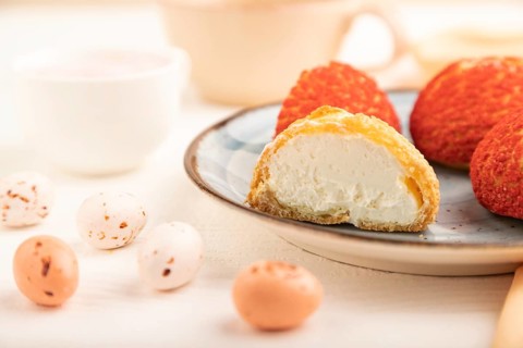 Traditional french custard dessert shu cake and cup of green tea on white wooden background and