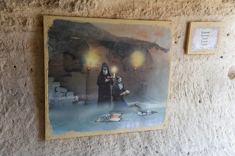 Mural painting with historical scene and information plaque on a cave wall, crypt, Aladja