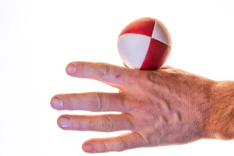 Hand with a juggling ball in front of a white background, studio shot, Germany, Europe