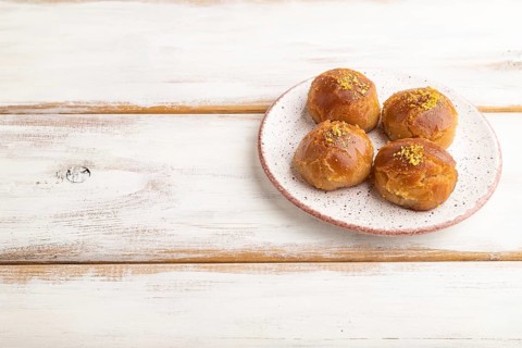 Homemade traditional turkish dessert sekerpare with almonds and honey on white wooden background.
