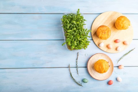 Homemade cakes with chocolate eggs and chrysanthemum microgreen on a blue wooden background. top