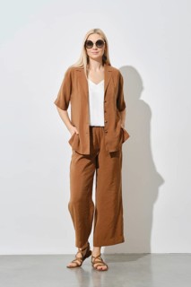 Cheerful blonde woman showcases a modern summer casual outfit. The loose brown suit and white inner