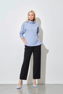 A modern fashion model posing with hands in pockets of classic black trousers wearing a stylish