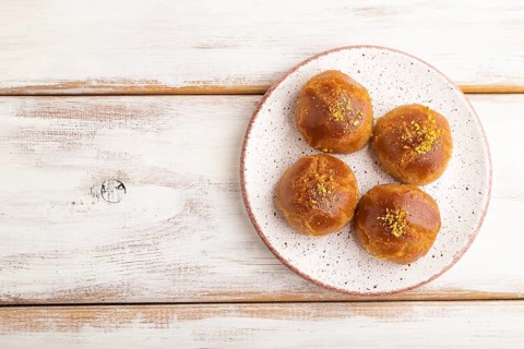 Homemade traditional turkish dessert sekerpare with almonds and honey on white wooden background.