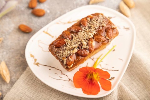 Caramel and almond cake with cup of coffee on brown concrete background and linen textile. side