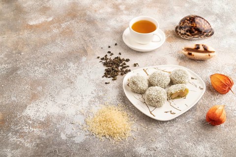 Japanese rice sweet buns mochi filled with pandan jam and cup of green tea on brown concrete