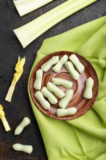 Jelly celery candies on black concrete background and green linen textile. close up, top view, flat