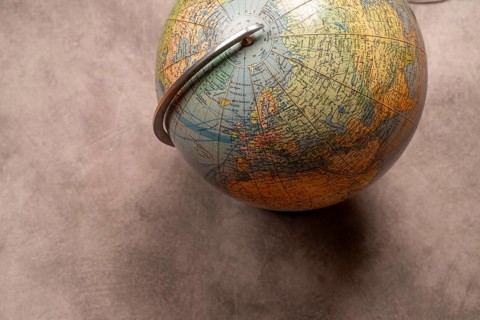 An old-fashioned globe on a grey texture with focus on the northern hemisphere, studio shot, top
