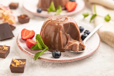 Chocolate jelly with strawberry and blueberry sliced with spoon on gray concrete background and