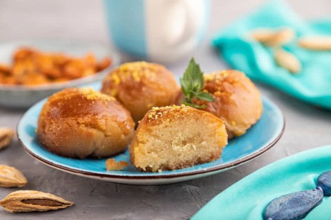 Homemade traditional turkish dessert sekerpare with almonds and honey, cup of green tea on gray