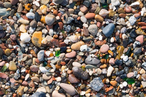 Close-up of different coloured pebbles, snail shell of a sea snail and smoothly ground glass
