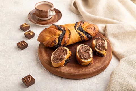 Homemade sweet bun with chocolate cream and cup of coffee on a gray concrete background and linen