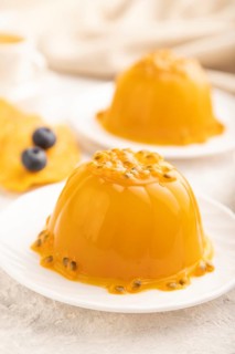 Mango and passion fruit jelly with blueberry on gray concrete background and linen textile. side