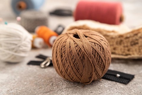 Sewing accessories: scissors, thread, thimbles, braid on brown concrete background. Side view,