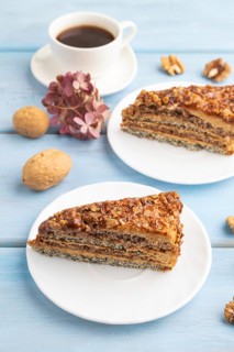 Walnut and hazelnut cake with caramel cream, cup of coffee on blue wooden background. side view,
