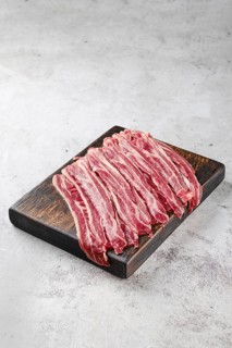 Fresh raw beef bacon strips on wooden cutting board