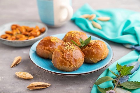 Homemade traditional turkish dessert sekerpare with almonds and honey, cup of green tea on gray