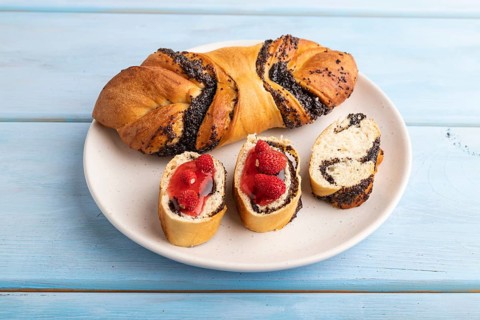 Homemade sweet bun with strawberry jam on a blue wooden background. side view, close up