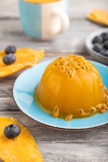 Mango and passion fruit jelly with blueberry on gray wooden background. side view, close up,
