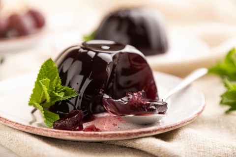 Black currant and grapes jelly on white wooden background and linen textile. side view, close up,