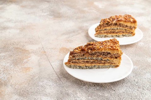 Walnut and hazelnut cake with caramel cream on brown concrete background. side view, copy space