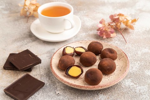 Japanese rice sweet buns chocolate mochi filled with cream and cup of green tea on brown concrete