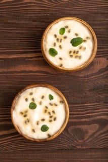 Yoghurt with granadilla and mint in wooden bowl on brown wooden background. top view, flat lay,