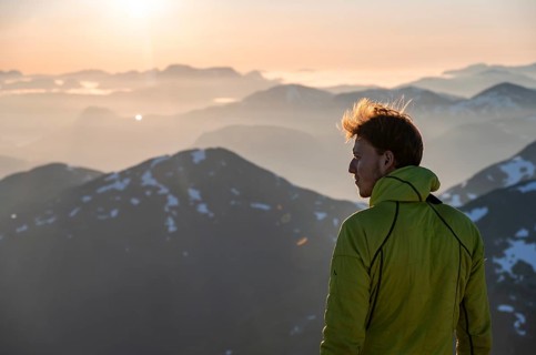 Mountaineer enjoying the view, mountain panorama at the summit of Skala at sunset, Loen, Norway,