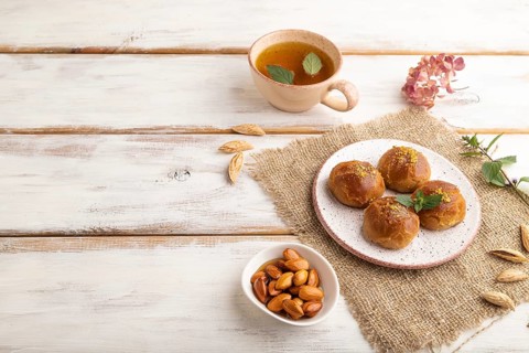 Homemade traditional turkish dessert sekerpare with almonds and honey, cup of green tea on white