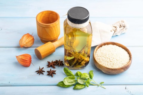 Sunflower oil in a glass jar with various herbs and spices, sesame, rosemary, star anise, basil on
