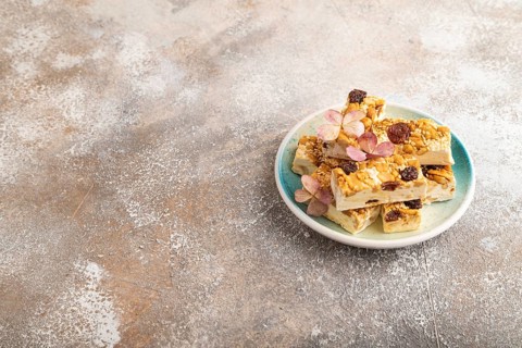 Traditional candy nougat with nuts and sesame on brown concrete background. side view, copy space