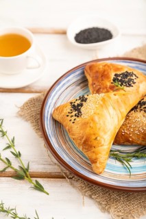Homemade asian pastry samosa, cup of green tea on white wooden background and linen textile. side